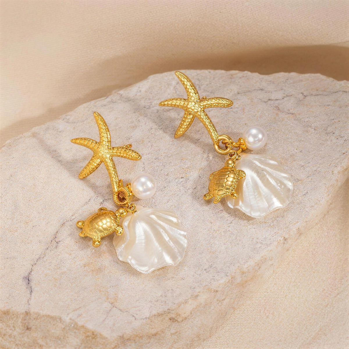 Gold starfish and turtle charm drop earrings with shell on stone