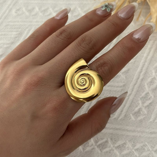 Gold spiral shell ring worn on the hand