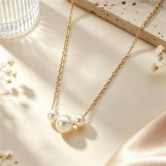 Trio pearl necklace on a gold chain laid on satin