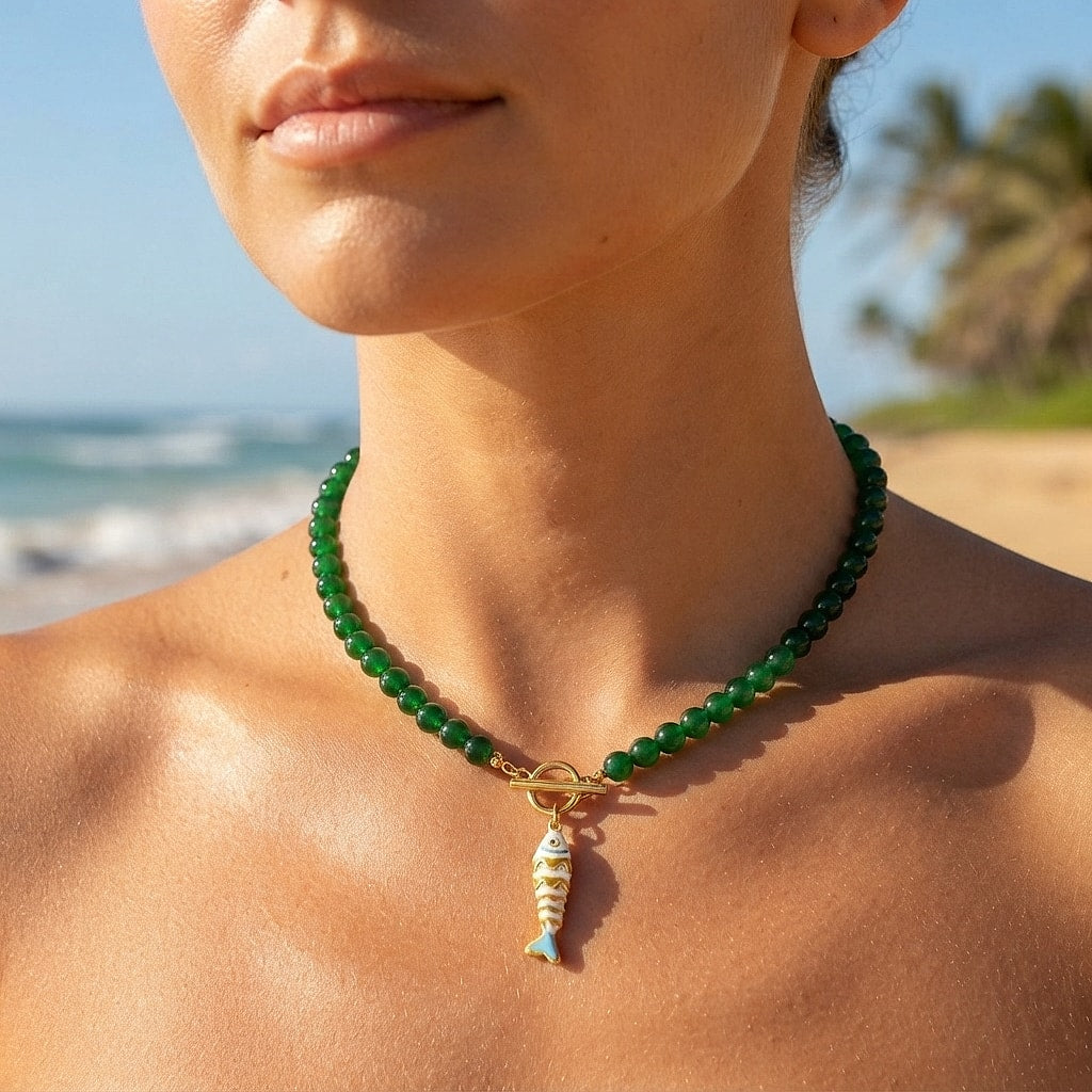 Dark green beaded koi fish necklace worn on a beach